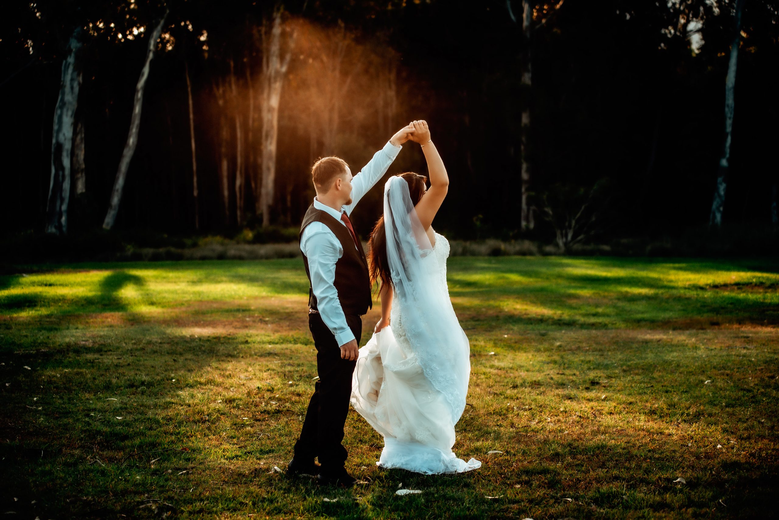bride and groom dancing in open field at sunset